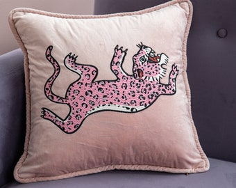 May include: A pink velvet pillow with a pink embroidered leopard design.