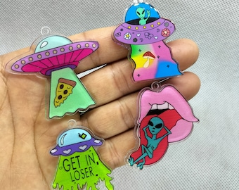 May include: Four acrylic alien-themed charms. One charm features a UFO with a slice of pizza, another shows a UFO with an alien inside, and a third has the text "GET IN. LOSER." The fourth charm depicts an alien relaxing on a tongue.