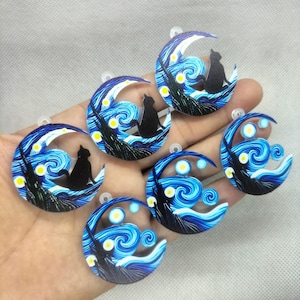 May include: Several circular pendants with a black cat silhouette on a crescent moon. The design is inspired by Van Gogh's "Starry Night", with swirling blue and white patterns, yellow stars, and a dark tree.