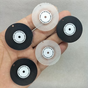 May include: Four black and white vinyl record-shaped charms with the text "MAKE LOVE RECORDS INC. - AMELODY EHSAHI PRODUTION" printed on them.