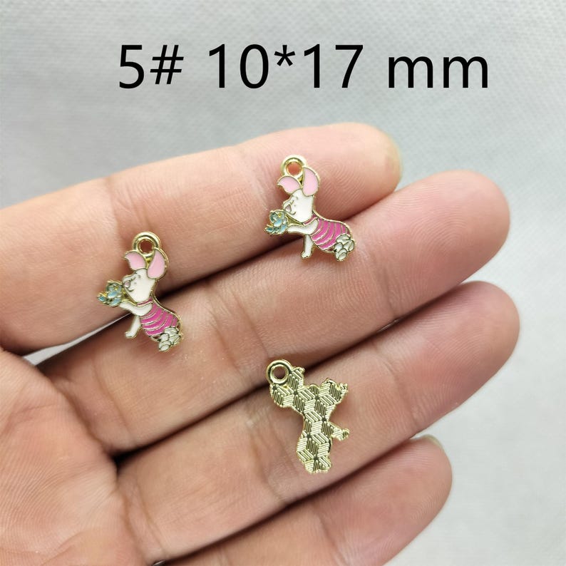 May include: Gold-toned metal charms featuring a pig design with pink and white enamel details. The charms are approximately 0.4 x 0.7 inches and have a loop for attaching to jewelry or crafts. The text "5# 10*17 mm" is visible.
