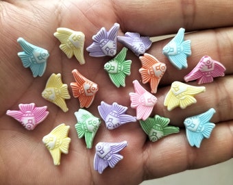 Może przedstawiać: Zbiór kolorowych, plastikowych guzików w kształcie ryb z białym tłem i misternymi wzorami. Guziki są w różnych pastelowych kolorach, w tym różowym, niebieskim, żółtym, zielonym i fioletowym.