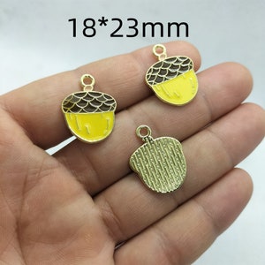 May include: Three gold acorn charms with yellow and brown enamel. The charms are 18mm by 23mm. The text '18*23mm' is visible in the image.