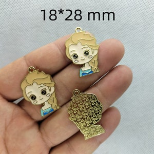 K&ouml;nnte beinhalten: Drei goldfarbene Metall-Anh&auml;nger, jeweils 18 x 28 mm gro&szlig;. Zwei Anh&auml;nger zeigen ein Cartoon-Bild eines M&auml;dchens mit blonden Haaren und blauen Augen, das ein blaues Kleid tr&auml;gt. Der dritte Anh&auml;nger ist eine Silhouette eines Personenkopfes mit einer strukturierten Oberfl&auml;che.