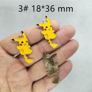 May include: Three gold-colored metal charms featuring a cartoon Pikachu character. The charms are 18 mm by 36 mm in size.