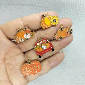 Könnte beinhalten: Sortiment aus sechs goldfarbenen Metall-Anhängern mit Kürbissen, Sonnenblumen und einem roten Lastwagen mit dem Text "Hello Autumn".
