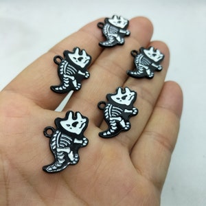 Può includere: Cinque ciondoli in metallo nero a forma di scheletro di dinosauro con vernice bianca. I ciondoli hanno la forma di un triceratopo.