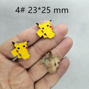 May include: Three gold-colored metal charms featuring a yellow cartoon character with red cheeks. The charms are 23 mm by 25 mm and are labeled "4# 23*25 mm".