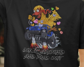 May include: Black t-shirt featuring a cartoon duck driving a blue off-road vehicle. The duck has a red face and yellow wings, with hearts and colorful lights. The text "DUCK AROUND AND FIND OUT" is below the graphic.