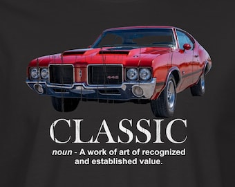 May include: A black t-shirt with a red classic car and the word "CLASSIC" in white text. The text below the car reads "noun - A work of art of recognized and established value."