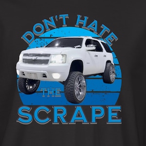 May include: Black t-shirt featuring a white SUV graphic with the text "DON'T HATE THE SCRAPE" in blue. The design includes a blue circle behind the vehicle. A small logo is on the left sleeve.