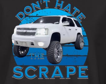 May include: Black t-shirt featuring a white SUV graphic with the text "DON'T HATE THE SCRAPE" in blue. The design includes a blue circle behind the vehicle. A small logo is on the left sleeve.