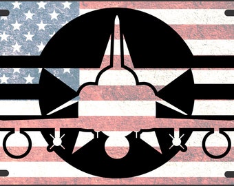May include: A black and white silhouette of a jet plane inside a circle with a star on a red, white, and blue American flag background.