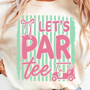 May include: A cream-coloured t-shirt featuring a distressed pink graphic that reads "Let's Par Tee". The design includes a golf cart and a bow. The background has vertical mint green and white stripes.