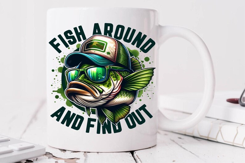 May include: White ceramic coffee mug with a green, black, and white illustration of a bass fish wearing sunglasses and a baseball cap. The text "Fish Around And Find Out" is printed on the mug.