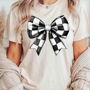 May include: A white t-shirt with a black and white checkered bow design.