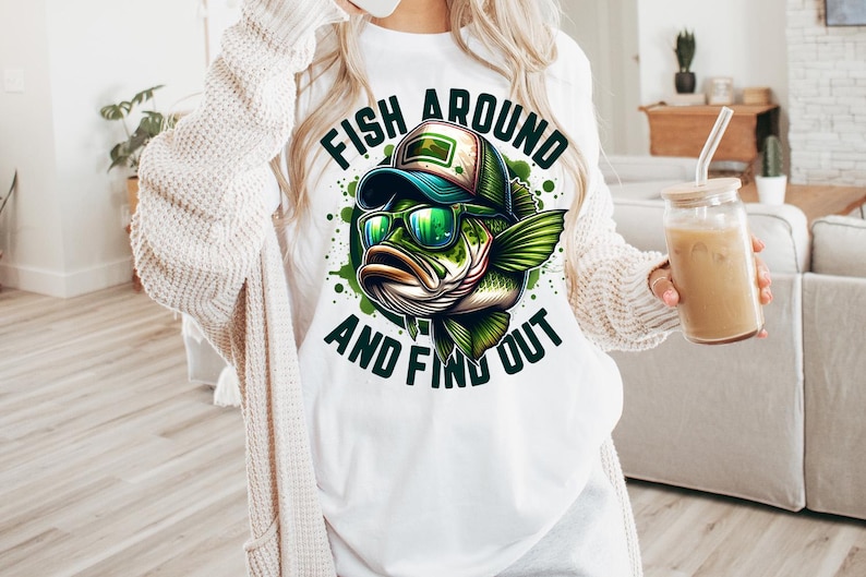 May include: White t-shirt with a green, blue, and black cartoon fish wearing sunglasses and a hat. The text "Fish Around and Find Out" is printed on the shirt.