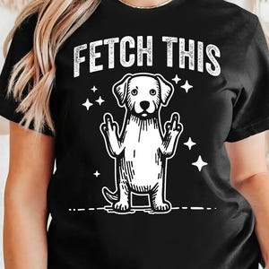 May include: Black t-shirt with a white graphic of a dog giving the middle finger with the text "FETCH THIS" above it.