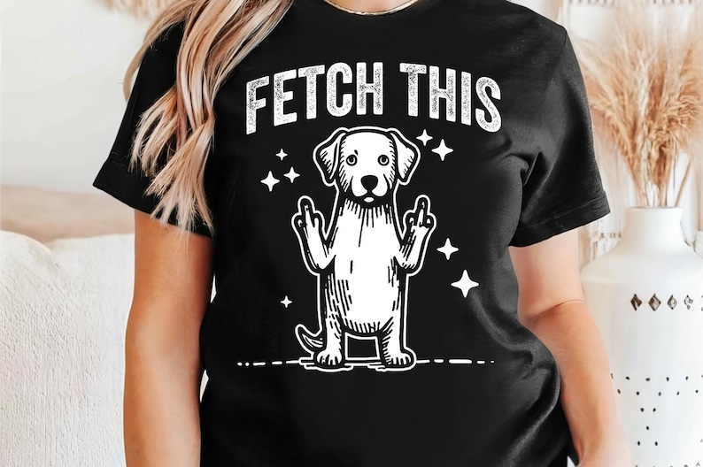 May include: Black t-shirt with a white graphic of a dog giving the middle finger with the text "FETCH THIS" above it.