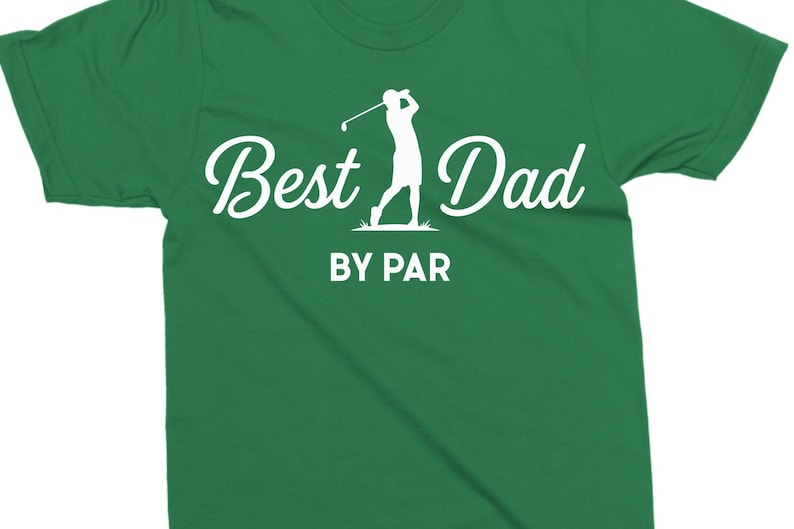 K&ouml;nnte beinhalten: Gr&uuml;nes T-Shirt mit dem Text "Best Dad" in Schreibschrift und einer Silhouette eines Golfspielers beim Schwingen eines Schl&auml;gers. Darunter steht "BY PAR" in einer serifenlosen Schriftart. Das Shirt hat eine einfarbige gr&uuml;ne Farbe.