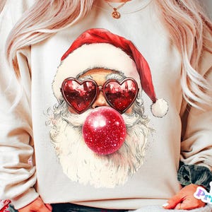 May include: A white sweatshirt featuring a cartoon illustration of Santa Claus wearing heart-shaped sunglasses and blowing a red bubble gum.
