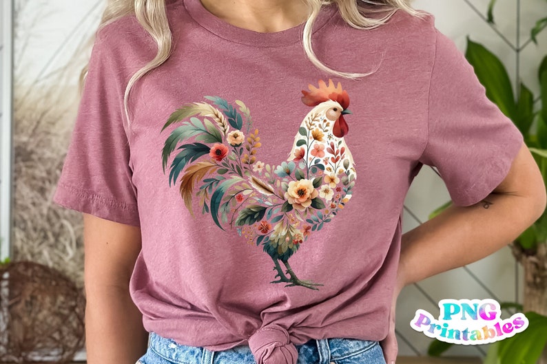 May include: A pink t-shirt with a floral rooster design. The rooster is made up of flowers and leaves in shades of pink, yellow, green, and brown.