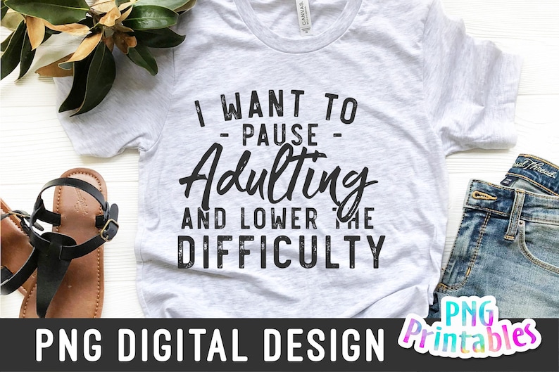May include: A white t-shirt with a black graphic that says "I want to - pause - Adulting and lower the difficulty".