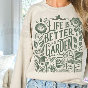 May include: A beige sweatshirt with a green floral design and the text "Life is better in the garden".