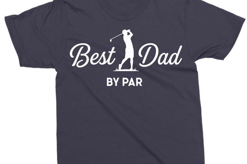 K&ouml;nnte beinhalten: Dunkelblaues T-Shirt mit dem Schriftzug "Best Dad" in Schreibschrift, begleitet von einer Silhouette eines Golfspielers. Der Satz "BY PAR" ist darunter in einer serifenlosen Schriftart gedruckt. Golf-Thema.