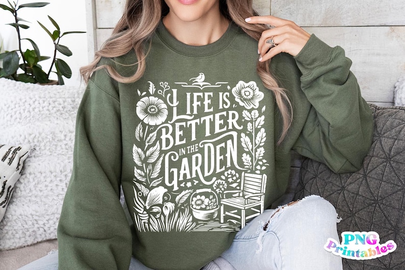 May include: A green sweatshirt with a white graphic design that says "Life is Better in the Garden". The design features flowers, leaves, a bird, a chair, and a pot.