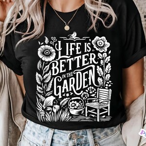 May include: A black t-shirt with a white graphic design featuring a floral motif and the text "Life is better in the garden".