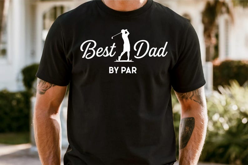 K&ouml;nnte beinhalten: Schwarzes T-Shirt mit dem Text "Best Dad" in Schreibschrift, begleitet von einer Golfspieler-Silhouette. Der Schriftzug "BY PAR" steht darunter. Das T-Shirt hat kurze &Auml;rmel.