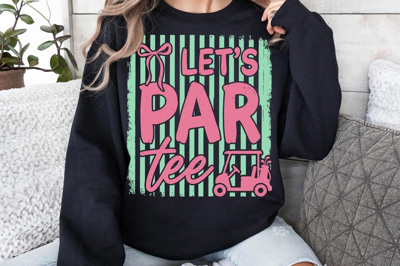May include: Black sweatshirt featuring the text "Let's Par Tee" in pink, with a golf cart and bow graphic. The design has green and black vertical stripes. A casual top for golf lovers. The measurements are in centimeters.