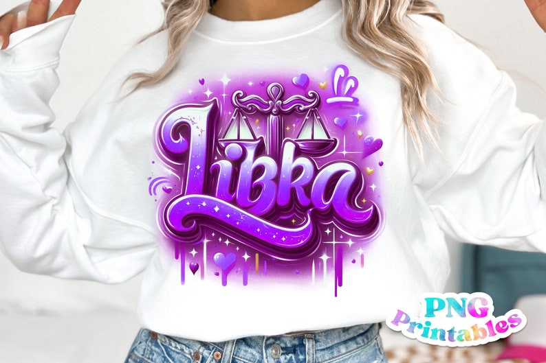 Pode incluir: Uma camisa de moletom branca com um design gr&aacute;fico roxo e dourado que apresenta a palavra "Libka" e um s&iacute;mbolo do zod&iacute;aco Libra. O design inclui cora&ccedil;&otilde;es, estrelas e gotas de tinta.