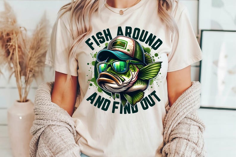 May include: A white t-shirt with a green and black cartoon fish wearing sunglasses and a baseball cap. The text "Fish Around And Find Out" is printed on the shirt.