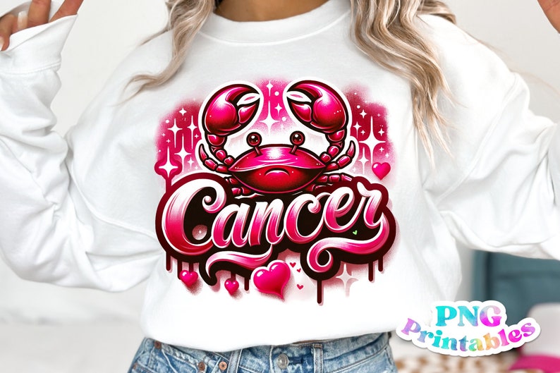 Pode incluir: Uma camisa de moletom branca com um design gr&aacute;fico rosa e preto de um caranguejo e a palavra "C&acirc;ncer". O design &eacute; cercado por cora&ccedil;&otilde;es e estrelas rosas.