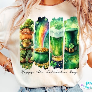 Puede incluir: Una camiseta blanca con un diseño de acuarela que presenta un duende sosteniendo una olla de oro, un arcoíris, un vaso de cerveza verde y un sombrero verde. El texto "Happy St. Patrick's Day" está impreso debajo del diseño.