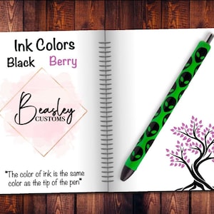 May include: A notebook with a green pen with alien faces printed on it. The notebook has the words "Ink Colors" and "Black Berry" written on it. The notebook also has the words "Beasley Customs" written on it. The text "*The color of ink is the same color as the tip of the pen*" is written at the bottom of the page.
