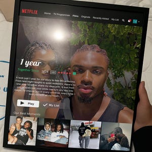 May include: A framed Netflix screen displays a couple's photo with the text "1 year Together Since 2024." The screen shows a "Play" button and a "My List" option, with additional images below. The frame is black.