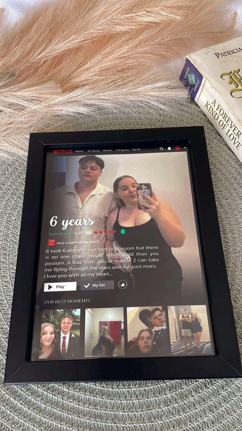 May include: A framed print featuring a Netflix-themed design with a couple's photo and the text "6 years." The black frame surrounds the image, which includes a screenshot with text and additional photos.