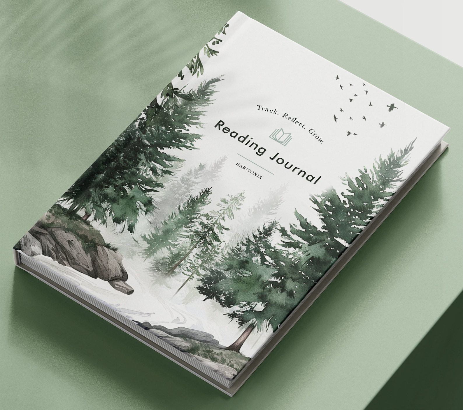 A "Reading Journal" with a forest-themed cover featuring green trees and birds against a light background, conveying a serene, reflective mood.