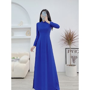 Puede incluir: Un vestido largo de color azul real con cuello alto y mangas largas. El vestido tiene un corpiño ajustado y una falda fluida.