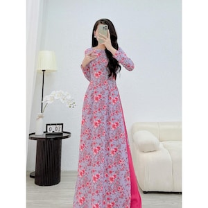 Könnte beinhalten: Ein langes, fließendes Kleid mit einem Blumenmuster in Lila- und Rottönen. Das Kleid hat lange Ärmel und einen hohen Ausschnitt. Das Kleid ist A-Linie und hat eine leuchtend pinkfarbene Seite.