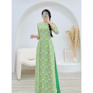 Puede incluir: Un vestido de estampado floral verde y blanco con forro verde. El vestido tiene un escote redondo y mangas tres cuartos.