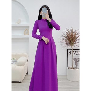 Könnte beinhalten: Ein langes, violettes Kleid mit einem Mandarinkragen und langen Ärmeln. Das Kleid hat einen taillierten Oberteil und einen fließenden Rock.