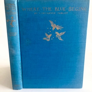 May include: A vintage book titled "Where the Blue Begins" by Christopher Morley. The book has a blue cover with gold lettering and illustrations of birds. The spine is also blue with gold text. A classic literary item.