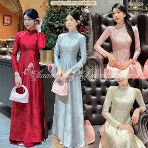 May include: Four long-sleeved dresses in red, light blue, pink, and cream. Each dress features a high collar and floral pattern. The dresses are displayed on models, showcasing the traditional Vietnamese Áo dài design.
