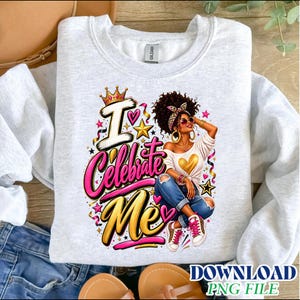 Può includere: Una felpa girocollo grigio chiaro con una stampa grafica di una persona con capelli ricci, fascia, occhiali da sole e un top bianco con un cuore dorato. Il testo recita I Celebrate Me in rosa e oro con stelle e una corona decorativa.