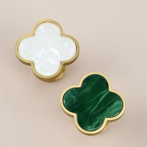 May include: Two brass clover-shaped cabinet knobs with a gold finish. One knob has a white mother-of-pearl inlay and the other has a green malachite inlay.