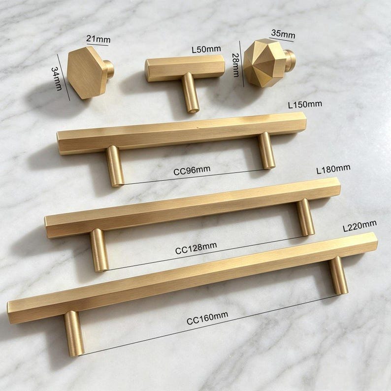 May include: A collection of brushed gold cabinet hardware including three hexagonal and T-shaped knobs and three long bar pulls. The hardware features labelled dimensions: knobs at 21mm by 34mm, 50mm by 28mm, and 35mm, with bar pulls at 150mm, 180mm, and 220mm lengths.